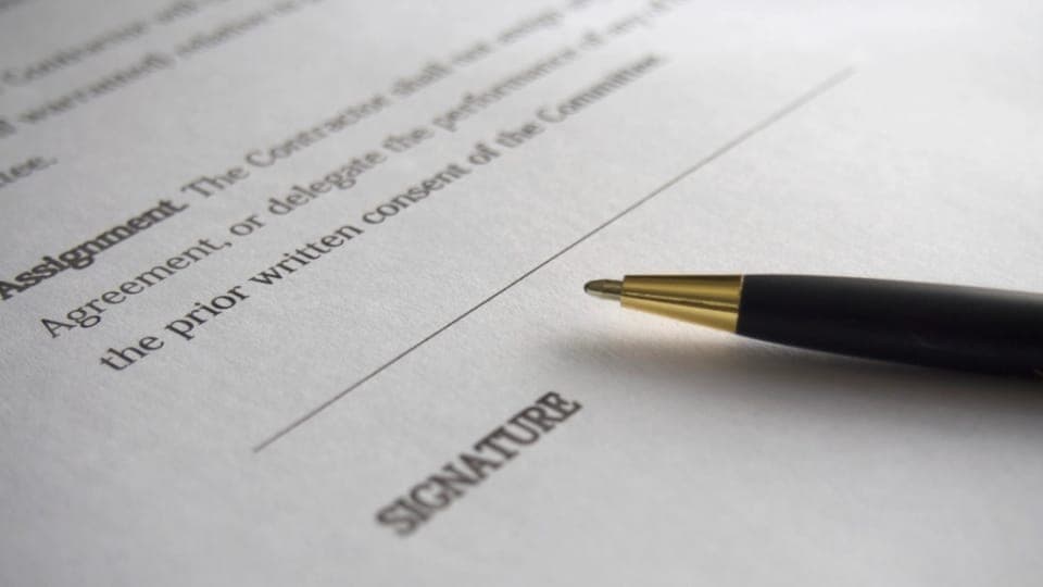 A pen resting on the signature line of a printed contract.